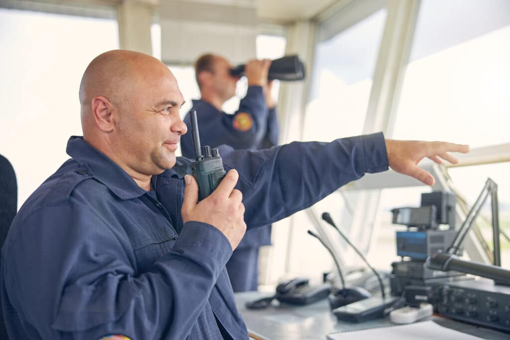 men in boat keeping watch with binoculars and walkie talkie