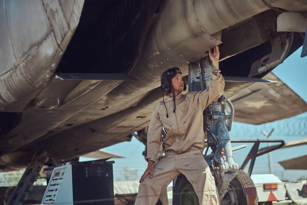 air force mechanic standing underneath plane
