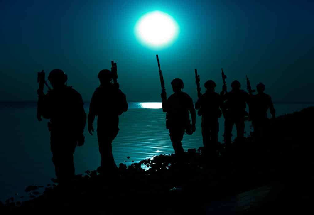 military soldiers walking along coast shore at night